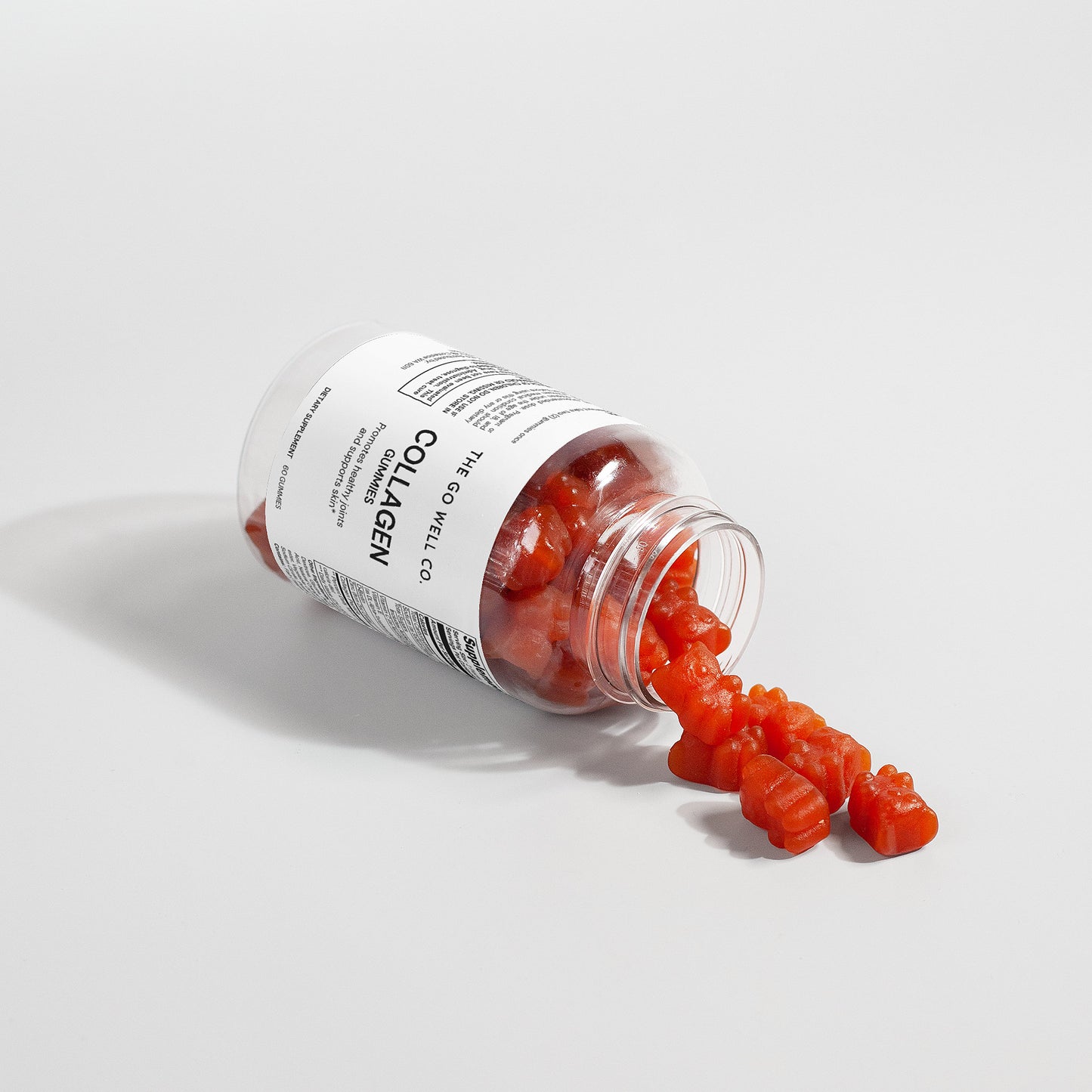 Bottle of collagen gummies spilling out onto a light gray background