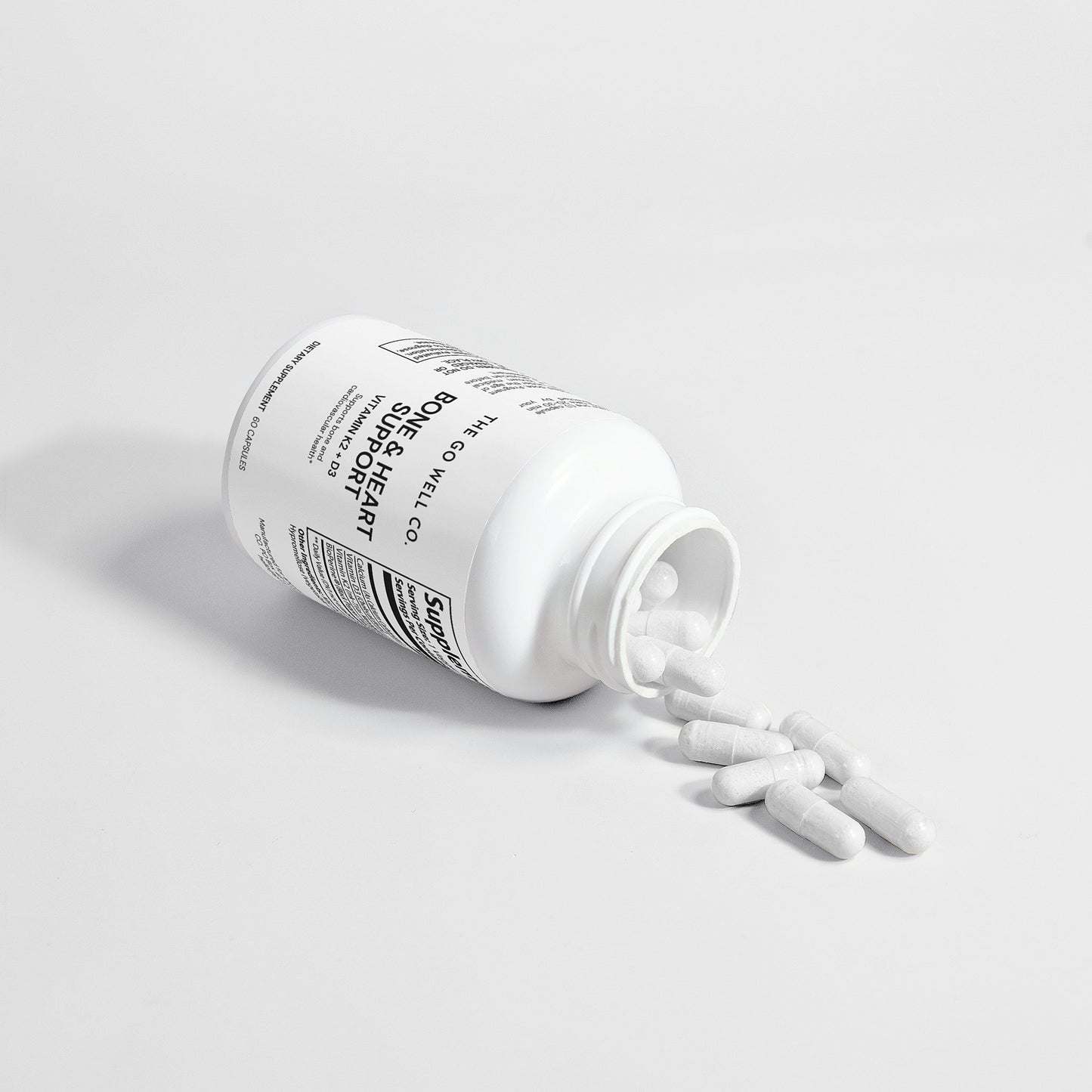 White bottle with capsules spilling on to a light gray background