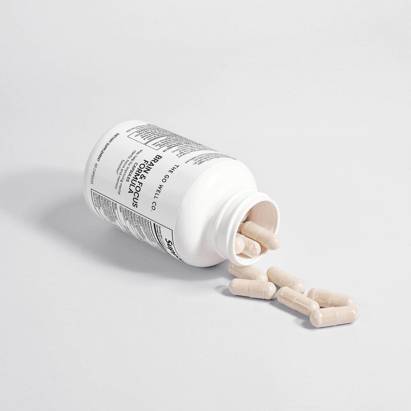 White supplement bottle with capsules spilling out on a light gray background