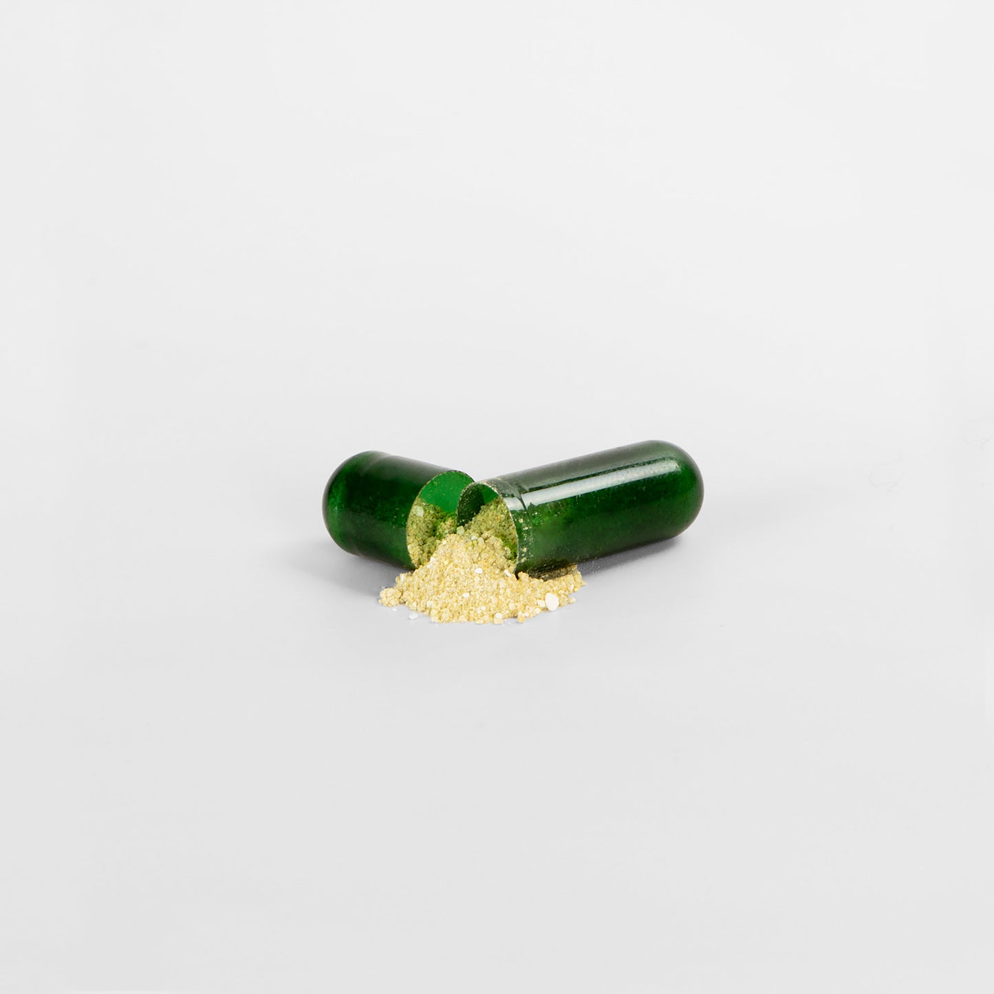 Green capsule with gold powder on a white background