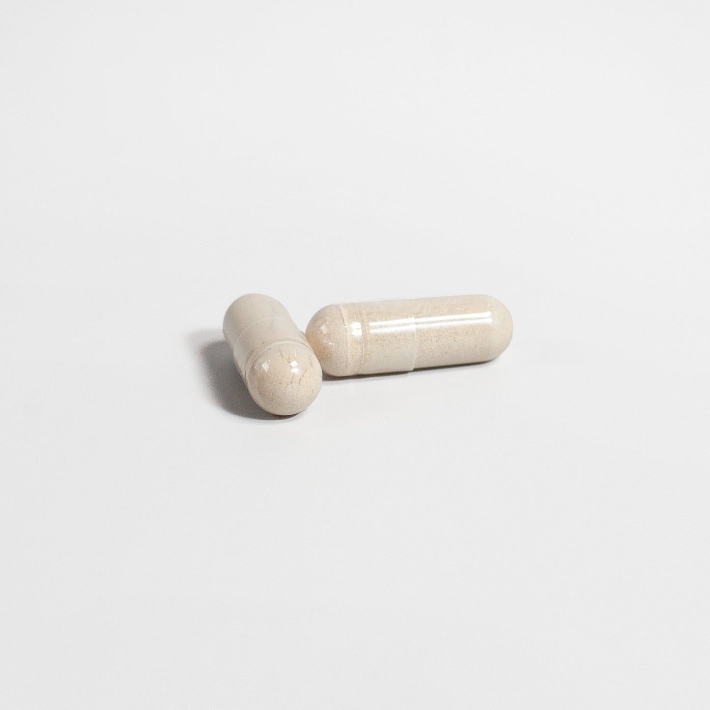 Two beige capsules on a light gray background