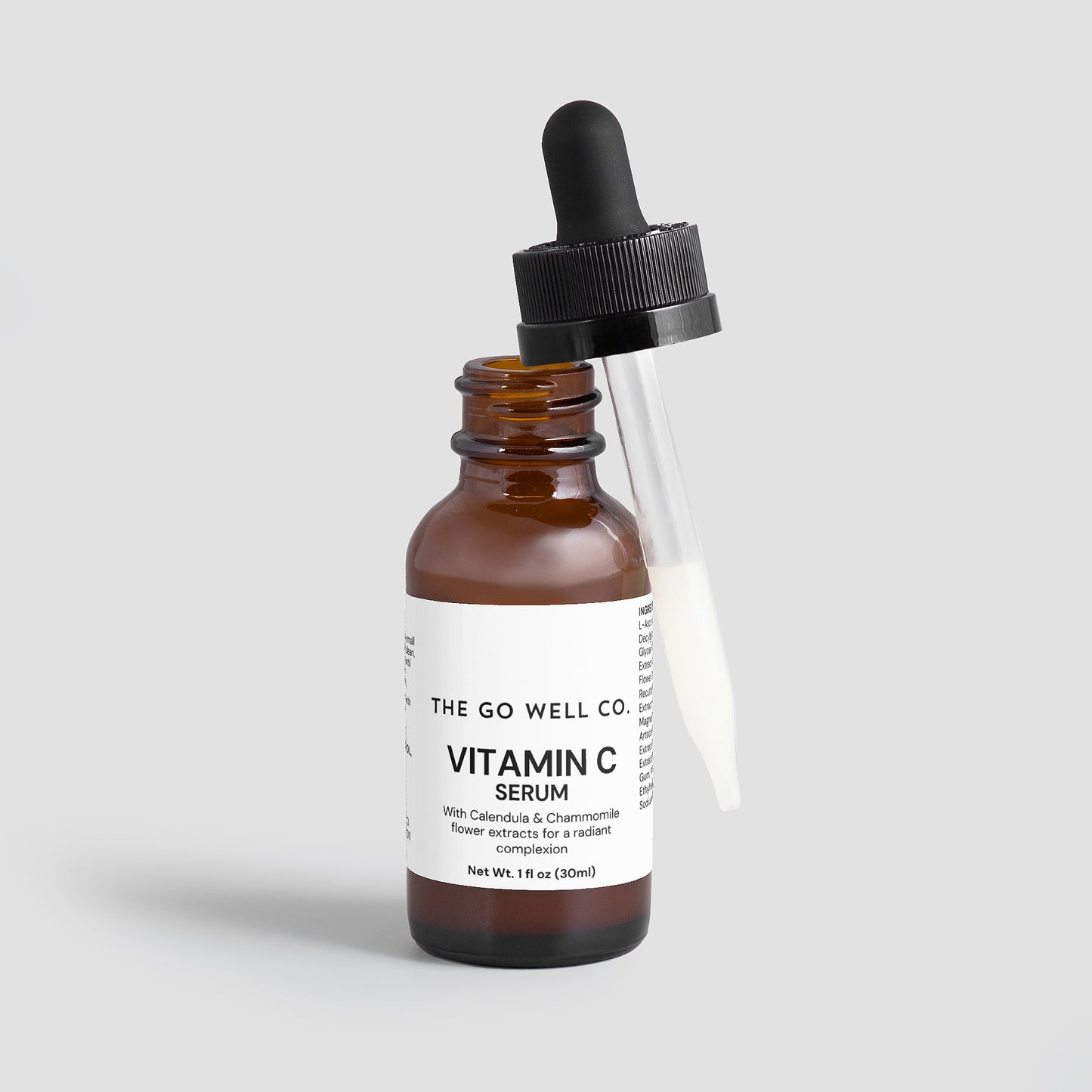 Vitamin C serum bottle with dropper labeled 'The Go Well Co.' on a light gray background