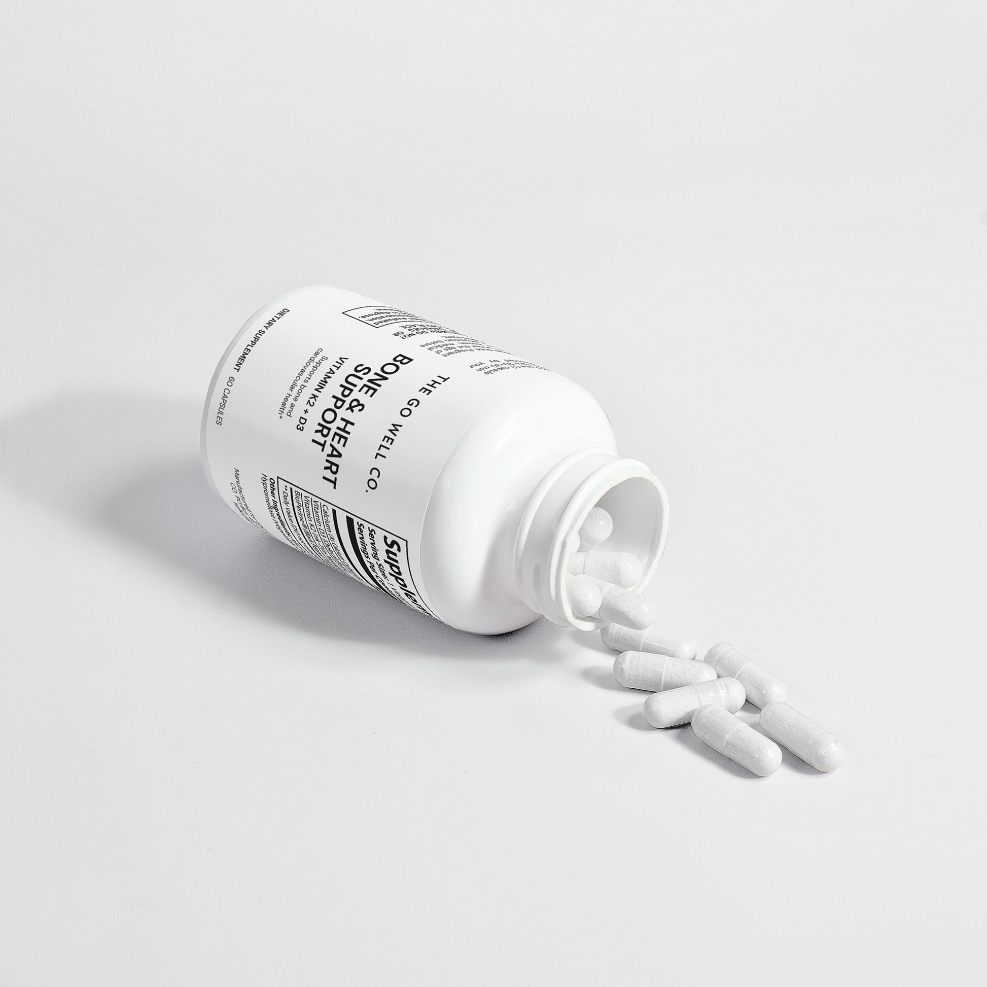 White bottle with capsules spilling on to a light gray background