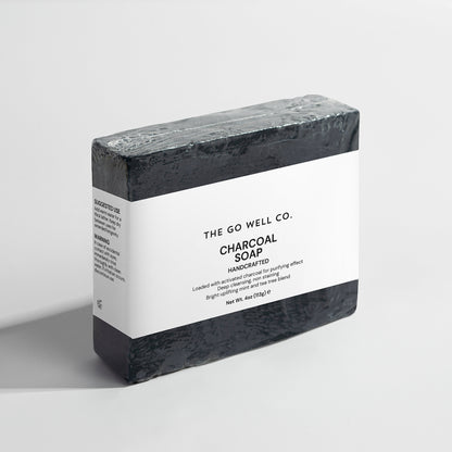 Bar of charcoal soap with a white label on a light gray background