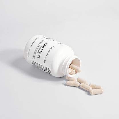 White supplement bottle with wooden figures spilling out on a light gray background