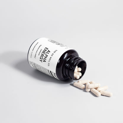 Alpha Energy supplement bottle with pills spilling out on a light gray background
