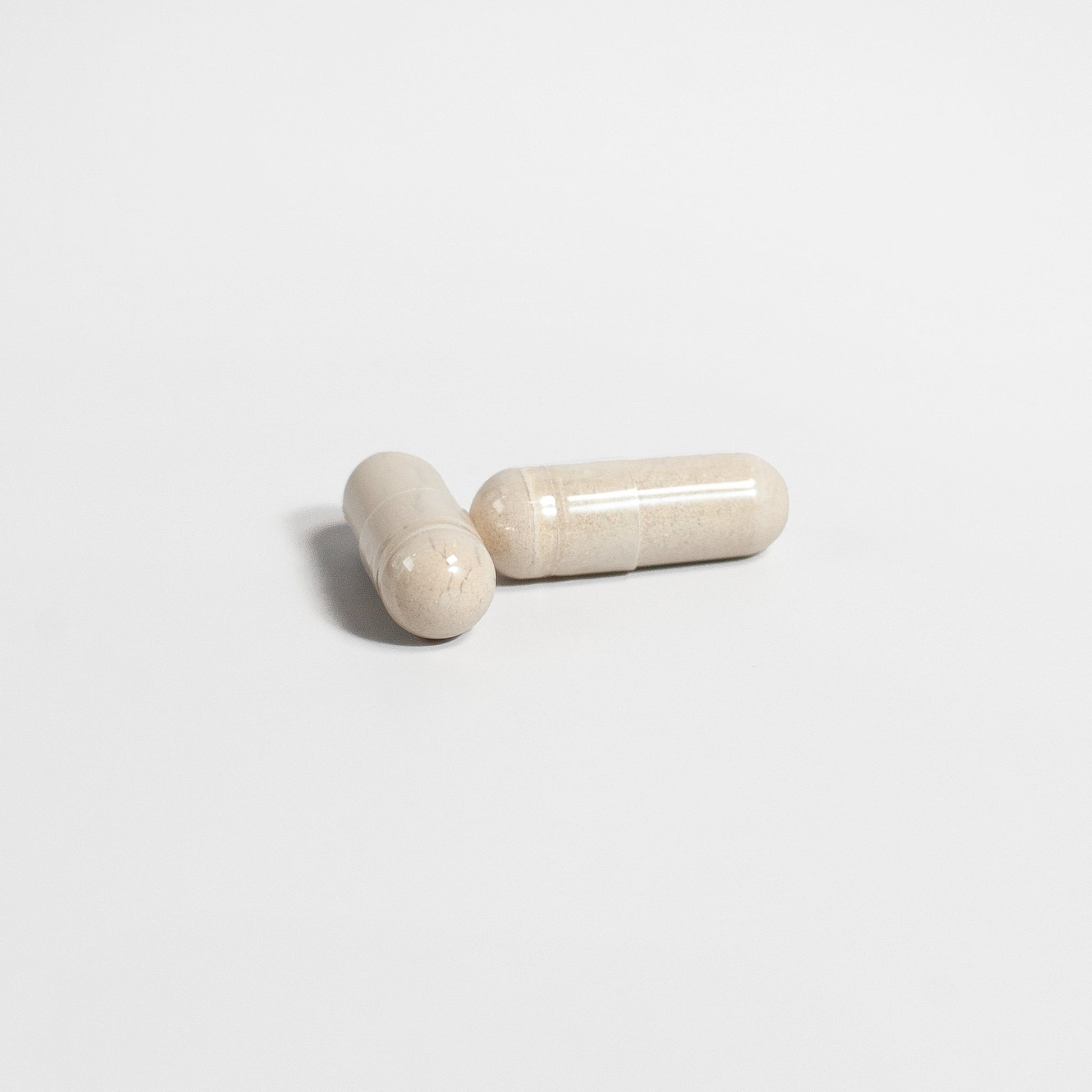 Two beige capsules on a light gray background