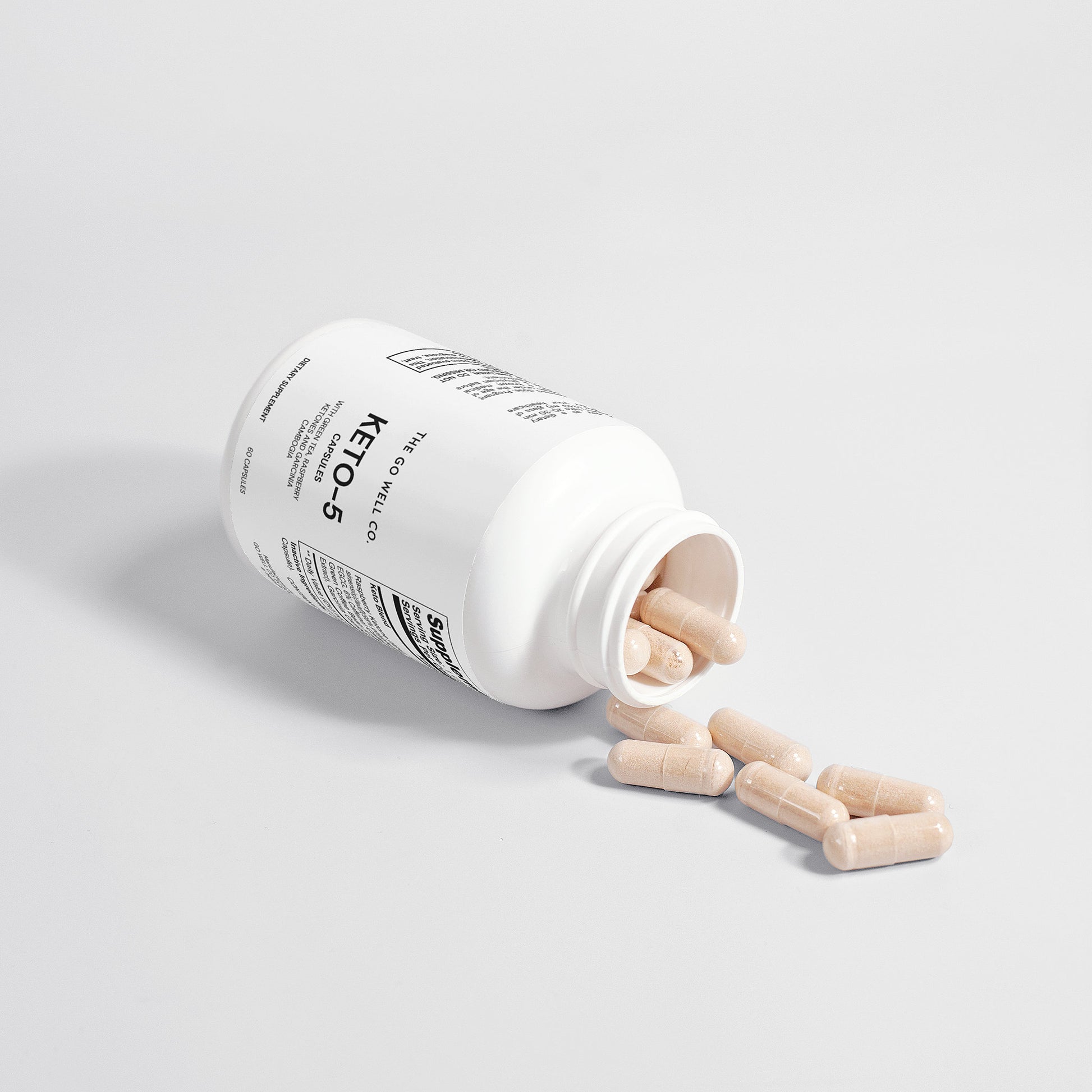White supplement bottle with pills spilling out on a light gray background